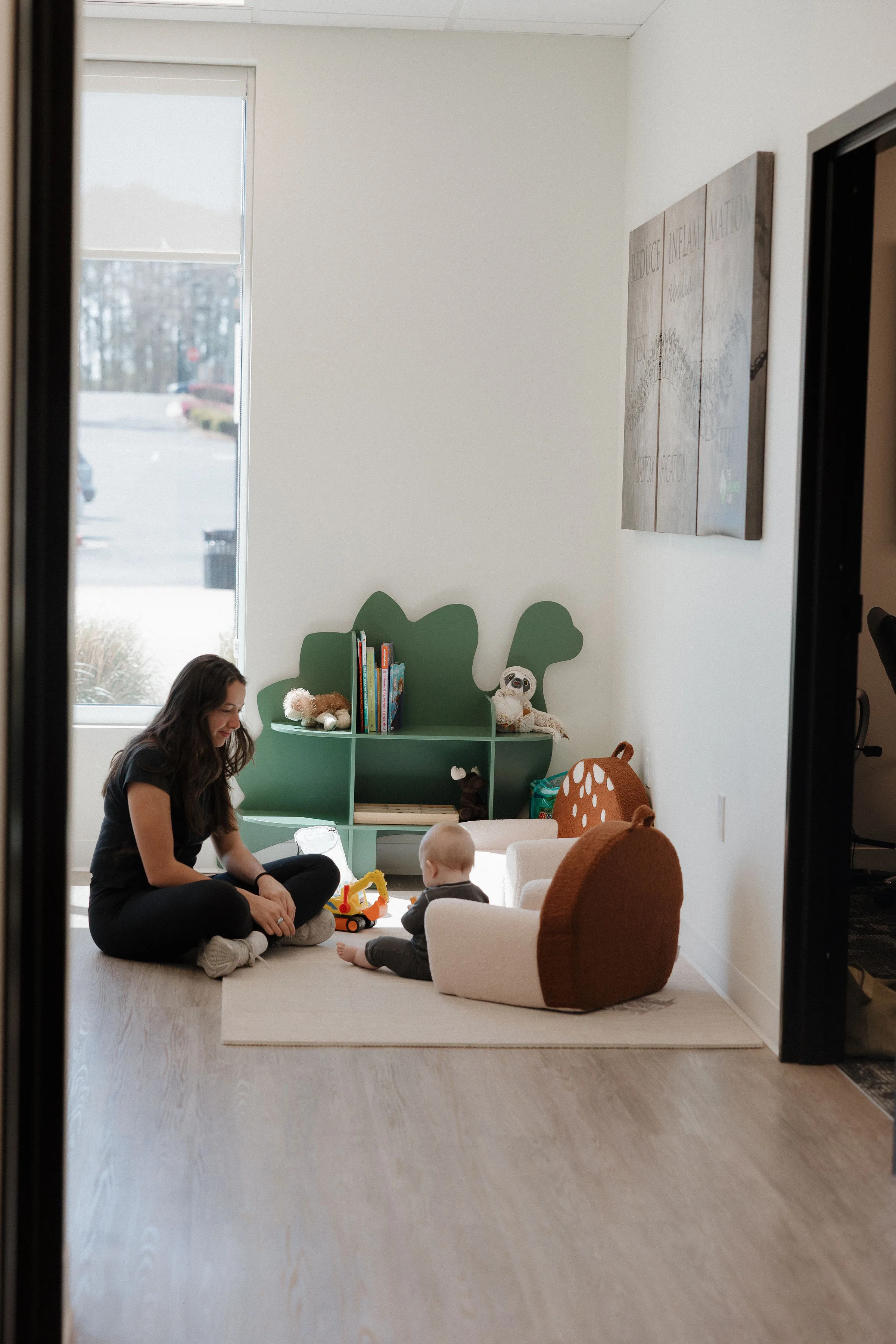 Family-friendly pediatric play room with green tree bookshelf at The Wellness Way - Mason