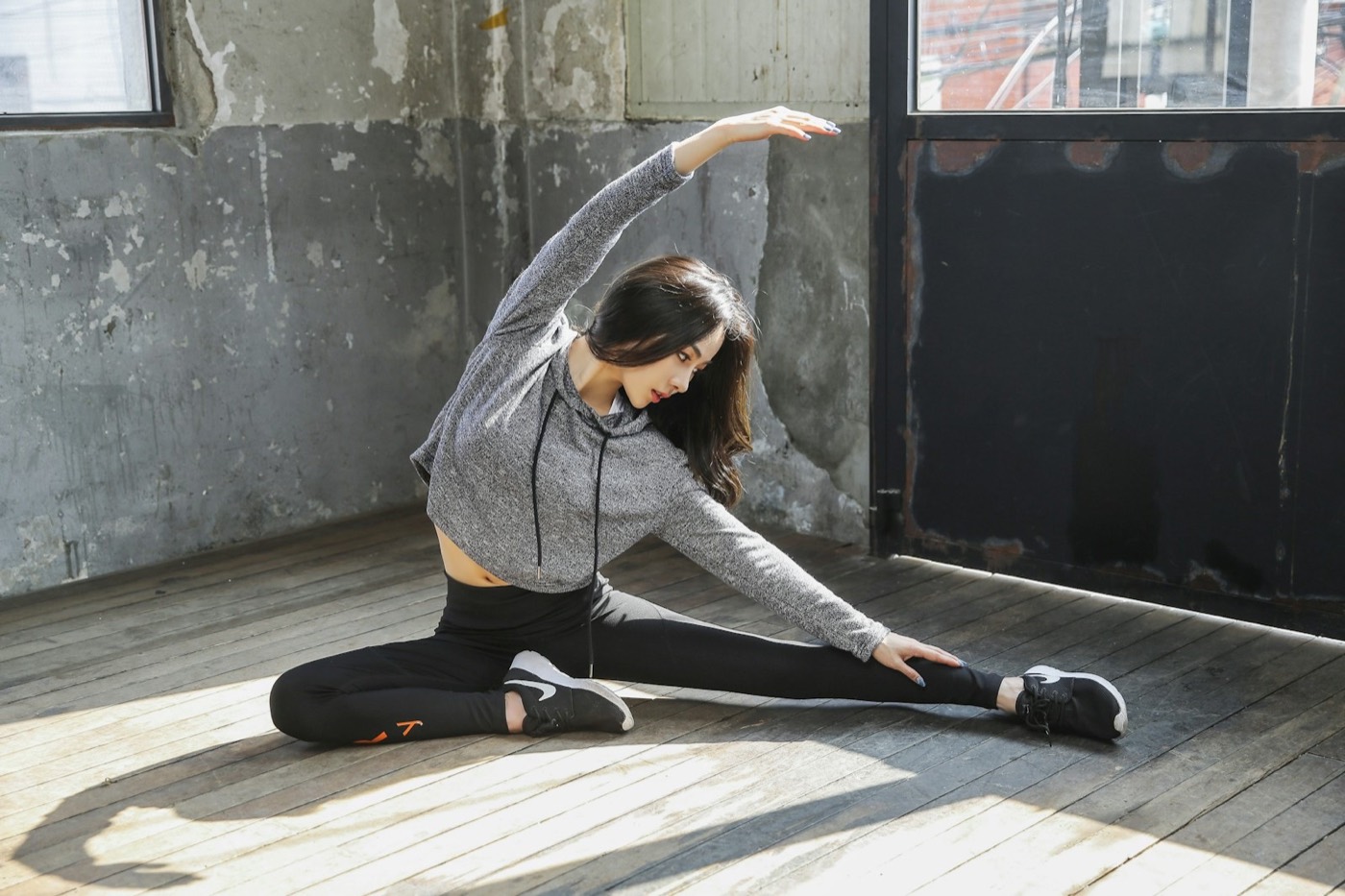 Woman doing a gentle stretch on a wooden floor — body-aware recovery and physical resilience