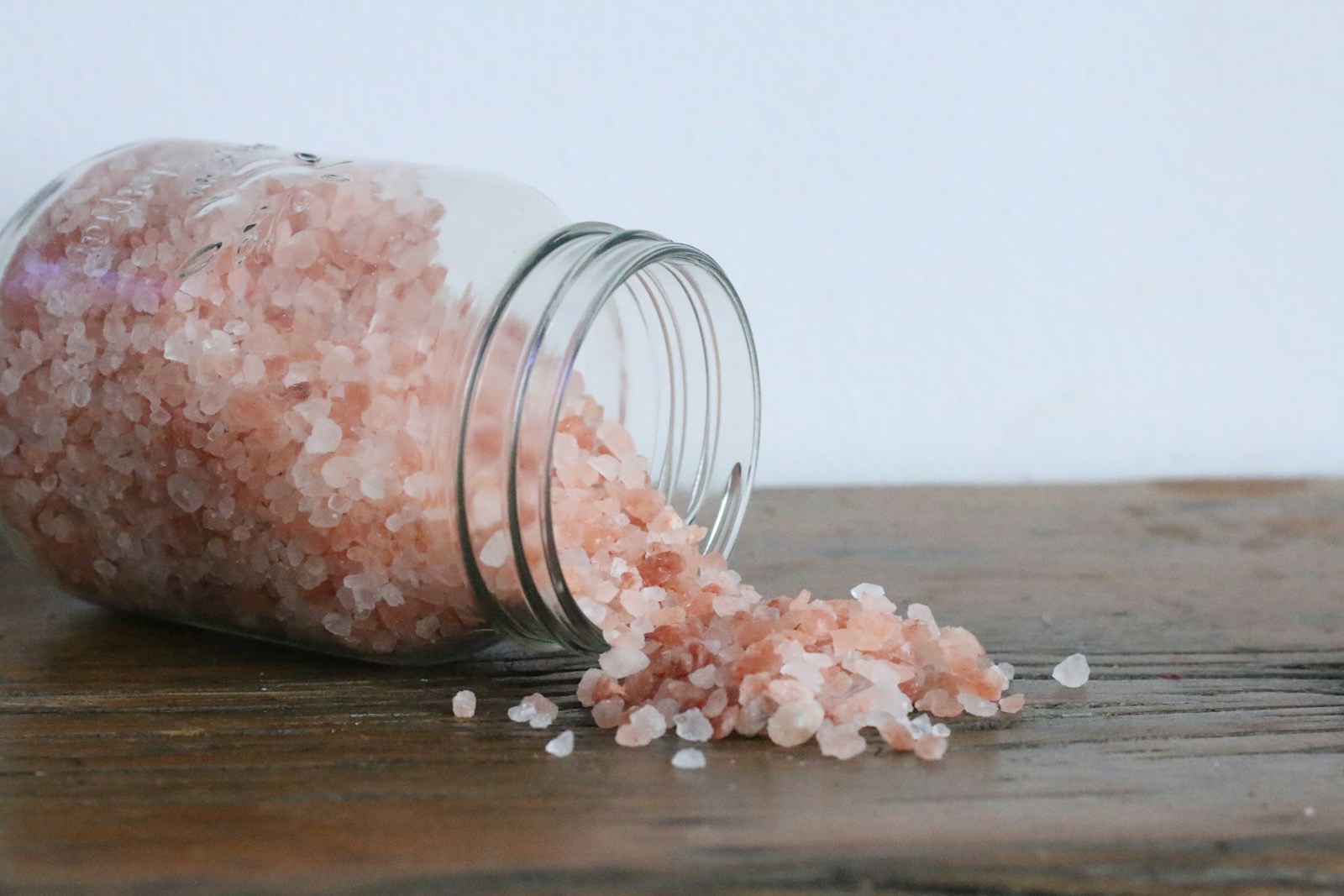 Pink Himalayan salt crystals in a clear glass jar — natural mineral salt