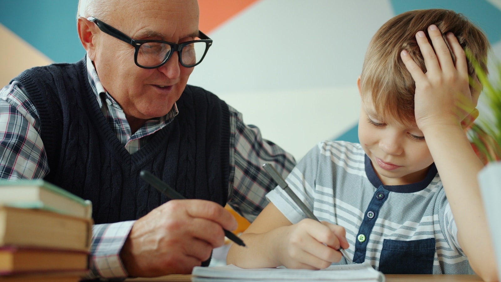 Older man and young boy doing homework together at a desk