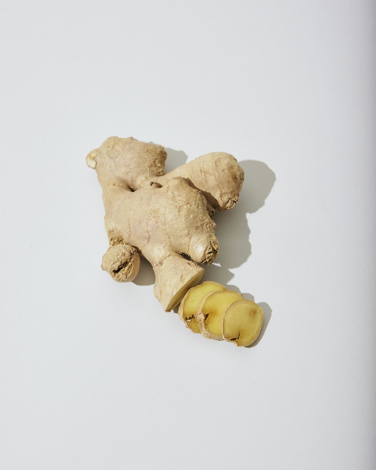Whole and sliced ginger root on a clean white surface — digestive support